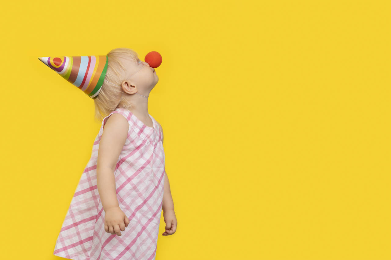 Hypnose fjerner klovnefobi, coulrofobi, angst for klovne. Lille pige med klovnenæse og hat kigger op.